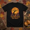 Black t-shirt with "Terrifying Visions Night Haunts" text, featuring a spooky tree, pumpkins, and a haunted house under an orange