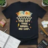 Black t-shirt with "Test Day You Got This Bruh. No Cap." text, open book graphic, and colorful retro design elements