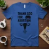 Blue t-shirt with black text "THANK GOD FOR ABORTION" above a stylized uterus graphic with roots and a lotus flower