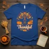 Thankful text with an autumn tree graphic, pumpkins, and cornucopia on a royal blue t-shirt