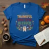 Thankful Grateful Blessed text design with praying hands and autumn leaves graphic on a royal blue t-shirt