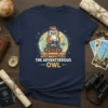 The Adventverous Owl T-Shirt design featuring a cute owl in a hat holding a camera, sitting on luggage with a