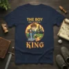 The Boy Who Would Be King t-shirt featuring a young knight pulling a sword from a stone with a castle