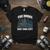 Black t-shirt with white and gold text "THE BRONX NEW YORK CITY" and a blue skyline graphic