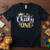 Black t-shirt with white and yellow text that reads "THE Cheeky ONE" and features a gold crown and hearts