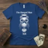 The Hanged Man Tarot XII design on a navy blue t-shirt, featuring an hourglass and lotus flower graphic