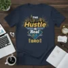 The Hustle Is Real Bro text with city skyline graphic on a dark blue t-shirt