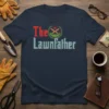 The Lawnfather t-shirt design with "The" in red and "Lawnfather" in distressed blue, featuring a laurel wreath with crossed gardening