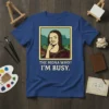The Mona Lisa with a finger in her nose, text reads "THE MONA WHO? I'M BUSY." on a royal blue