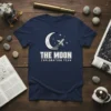 The Moon Exploration Team text with a crescent moon and rocket graphic on a navy blue t-shirt