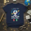 The Moon Is Calling... text with a rocket launching towards the moon, on a navy blue t-shirt