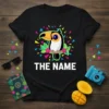 Black t-shirt with "THE NAME" text and a colorful toucan graphic surrounded by confetti and leaves