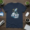 Navy blue t-shirt featuring the text "THE NEW GUY" with a rocket launching into stars and clouds