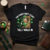 Black t-shirt with white text "THE PADDY DON'T START TILL I WALK IN" and a cartoon leprechaun walking through a