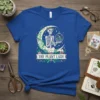 The Plant Lady T-Shirt with skeleton sitting on moon holding terrarium, floral wreath, and plant motifs