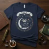 The Reader of Stars t-shirt design featuring an owl reading on a crescent moon surrounded by stars and celestial elements