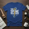 The Spine Whisperer t-shirt design featuring white text and a Caduceus-like symbol with a spine graphic and EKG wave