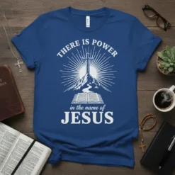 Christian T-Shirt with "There Is Power In The Name Of Jesus" text, cross on a mountain, and open Bible graphic