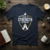 Navy t-shirt with white text "There Is Strength In Prayer" inside a shield graphic with praying hands and a dove