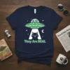 They Are REAL t-shirt design with a black cat being abducted by a green UFO, featuring two aliens and stars