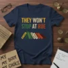 Navy t-shirt with yellow, green, and red text reading "THEY WON'T STOP AT ROE," below which are book spines labeled