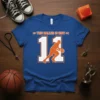 Blue t-shirt with orange and white text "THIS BALLER IS NOW" and a basketball player silhouette dribbling number 11