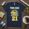 This Dad Is Officially 21 T-Shirt with a muscular dad holding a baby graphic and bold text