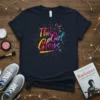 This Girl Glows colorful text design on a navy blue t-shirt with bright starbursts and sparkles