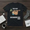 Graphic t-shirt design with text "THIS IS MY BACKWARDS DAY SHIRT" and a cartoon sloth hanging from a branch