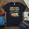 This Is My Field Trip Shirt graphic tee with an orange school bus, dinosaur skeleton, pyramid, and rocket ship