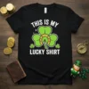 White text "This Is My Lucky Shirt" above a green shamrock with a golden horseshoe, on a black t-shirt