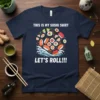 Navy blue t-shirt with "THIS IS MY SUSHI SHIRT LET'S ROLL!!!" text and a graphic of various sushi rolls and