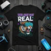 Black t-shirt with "THIS JUST GOT REAL" text and a tiger wearing VR goggles on a neon grid background