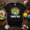 Black t-shirt with "Awesome Since 2022 Three Rex" text and a cartoon green dinosaur holding a '3' balloon