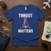 Blue t-shirt with white text "THRUST MATTERS" and a graphic of a red and blue rocket launching with orange flames