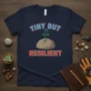 Navy t-shirt with "Tiny But Resilient" text and a seedling growing from a rock with a raised fist symbol