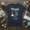 Tired. Tired.* quote on a navy t-shirt with a sleepy moon character holding a coffee cup