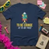 Navy t-shirt with yellow and white text "To Be Cringe Is To Be Free" above a cartoon rocket ship graphic