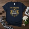 Navy blue t-shirt with gold text "Too Gorgeous To Be Bothered" in a decorative crest with lions and crown