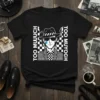 Black t-shirt with "TOO MUUCH TOO MUYOGH" text and a crying character in a fedora and checkered shirt