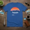 Toronto Toronto skyline graphic t-shirt featuring a sunset over city buildings and a ferry boat, with text "Toronto Toronto"