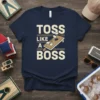 Navy t-shirt with "Toss Like A Boss" text and a graphic of a cornhole board with bags