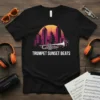 Trumpet Sunset Beats text and trumpet graphic on a black t-shirt, with a retro city skyline and sunset background