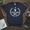 Navy blue t-shirt with white text "TRUST GOD BRO" inside a laurel wreath, praying hands, and a dove graphic