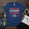 Trust Me I'm Almost A Nurse t-shirt design with bold red and white text, caduceus symbol, and heartbeat graphic