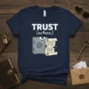 Navy blue t-shirt with white text "TRUST (no one.)" above a graphic of a cracked safe with an eye and
