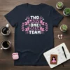 Text "TWO LADIES ONE DREAM TEAM" in pink and white with decorative elements on a navy t-shirt
