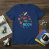 Blue t-shirt with "TWO THE MOON" text, rocket, stars, and flowers graphic for a second birthday celebration