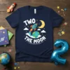 Navy blue t-shirt with "TWO THE MOON" text, a rocket blasting off, and a smiling moon