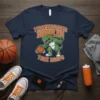 Tyrannosaurus Dribbles Trex Hoops T-Shirt featuring a green T-Rex dribbling a basketball with text above and below